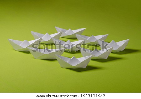 Concept photo for your project. White origami on green background. Group of handmade ship.