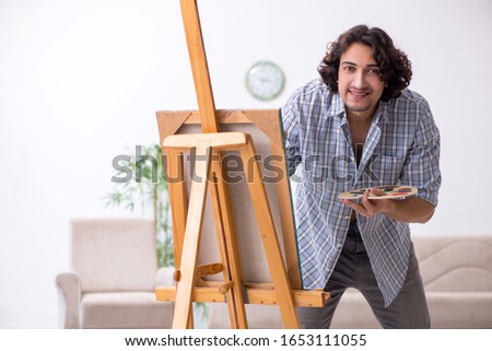 Young handsome man enjoying painting at home