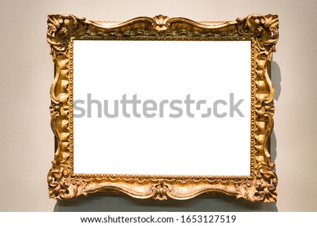 horizontal baroque picture frame with cutout canvas hangs on wall lit by electric light