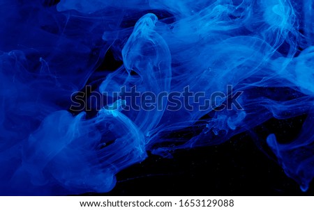 Blue watercolor ink in water on a black background. Colored space background. Abstract background. Stylish trending screensaver.