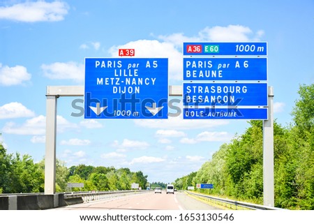 Traffic sign on the highway, toll or autoroute in France with big sqaure blue board ,road  number A39 ,A36  direction to Paris and another city's names in french language . Transport and sign concept.
