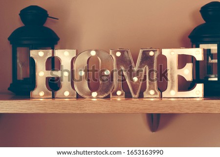 Idea of interior decoration with metal illuminated letters making home word on a wooden shelf