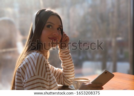 Woman listening to audiobook at table in cafe