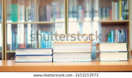 Pile of business books on study desk in library self access learning room, textbooks at school, college, or university, education or academic concept picture related to research, selective focus mode 