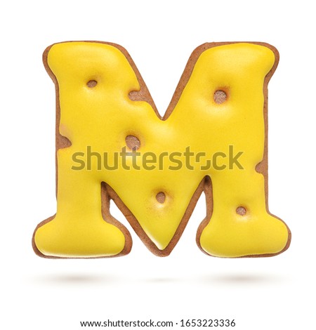 Capital letter M yellow homemade gingerbread biscuit isolated on white background.