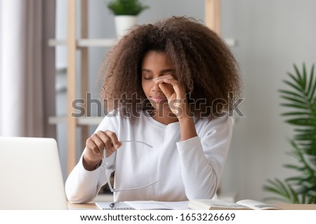 African teen school student tired from computer holding glasses, fatigued black teenage girl feel tension eyestrain pain rubbing irritated eyes suffer from bad eyesight blurry vision problem concept Royalty-Free Stock Photo #1653226669