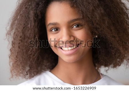 Head shot of african american teen girl looking at camera, black female adolescent teenager with pretty face posing alone, smiling teenage generation z school child with afro hair close up portrait Royalty-Free Stock Photo #1653226909