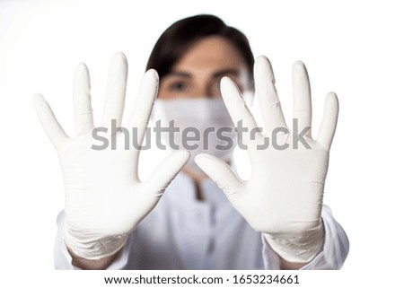 Female doctor in white medical uniform with a gloved hand showing a stop sign. Medical infects stopping concept