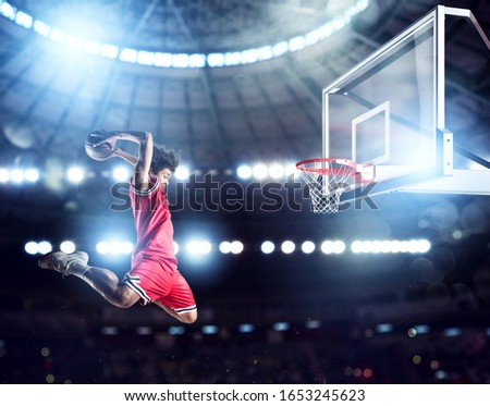 Jumping Player throws the ball in the basket in the stadium full of spectators