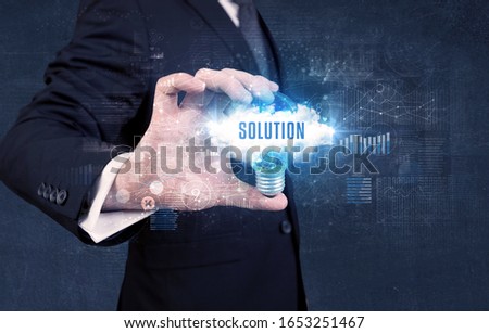 Businessman holding a light bulb with SOLUTION inscription, new business concept