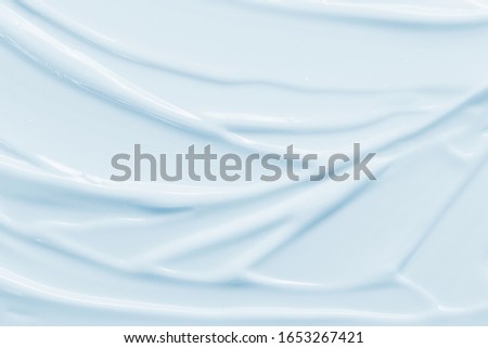 Cosmetic cream texture background. Moisturizer, lotion smudged. Light blue color creamy skincare product strokes closeup