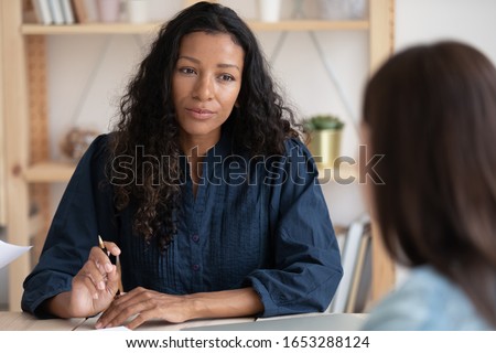 Head shot focused african american female leader boss supervisor listening to employee at meeting. Concentrated biracial hr manager holding job interview. Mixed race businesswoman consulting client. Royalty-Free Stock Photo #1653288124
