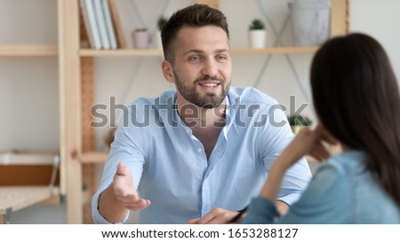 Head shot young man involved in conversation with colleague in office. Happy coworkers chatting talking speaking, enjoying break time at workplace. Smiling job seeker introducing himself at interview. Royalty-Free Stock Photo #1653288127