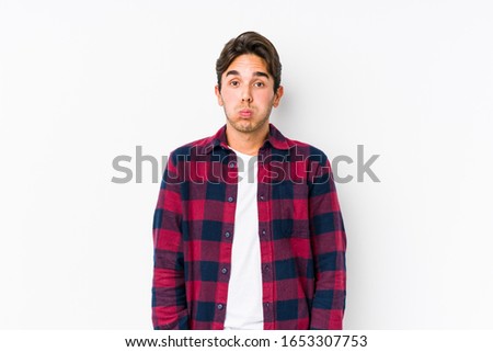 Young caucasian man posing in a pink background isolated blows cheeks, has tired expression. Facial expression concept.