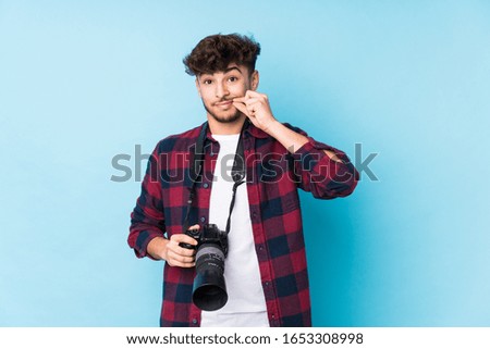 Young arab photographer man isolated with fingers on lips keeping a secret.