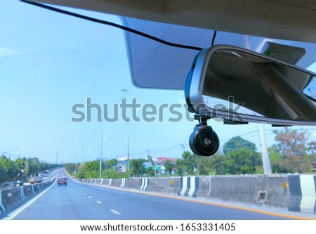 Picture of front window of the car with mirror and surveillance camera (focus at camera)