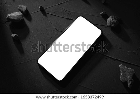 Phone top view with white screen for your text image on concrete, stone background. Hard light and the shadows