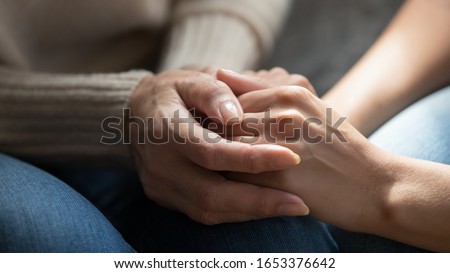Close up middle aged mommys wrinkled hands holding young daughters, millennial woman supporting mature mum, showing care, love. Asking for apologize, forgiveness, reconcile after quarrel gesture. Royalty-Free Stock Photo #1653376642