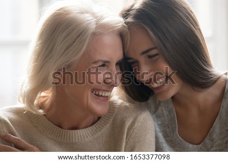 Head shot close up portrait happy smiling mature mother and grown up adult daughter bonding, touching foreheads, laughing, having fun together, enjoying free time together, two generations relations. Royalty-Free Stock Photo #1653377098