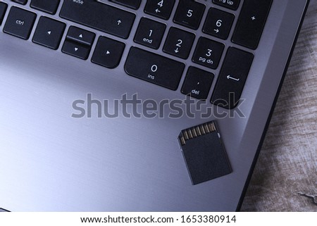 Micro SD memory card adapter on laptop background on the wooden table. close up