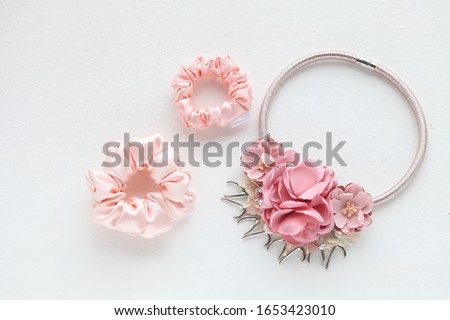 Pink hair accessories with roses. silk Pink Scrunchy isolated on white backdrop. Flat lay Hairdressing tools and accessories as Color Hair Scrunchies, Elastic HairBands, Bobble Scrunchy Hairband Royalty-Free Stock Photo #1653423010