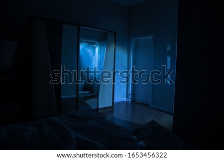 A creepy bedroom scenery, Silhouette of scary person standing reflected in mirror with mist and toned light. Horror Halloween concept