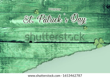 Happy St. Patrick's Day. Good luck charm on the view on the dark green wooden table with Shamrocks. And the torn paper in the bottom right corner