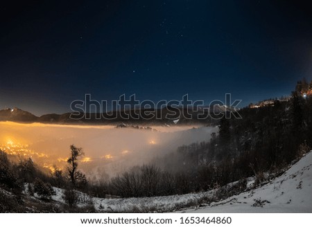 Brasov city covered with fog at late hour in winter night with clear sky 