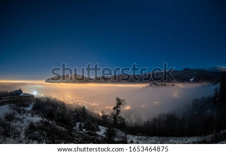 Brasov city covered with fog at late hour in winter night with clear sky 