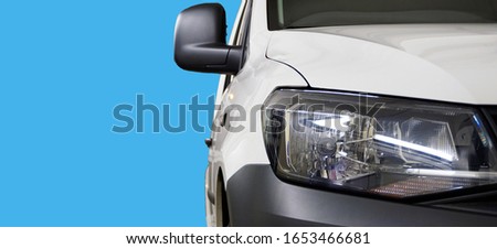 Concept. Service and repair of a modern car. Sale of high-quality spare parts for a modern car. In the photo the front of the car, close-up headlamp, plain background in blue.