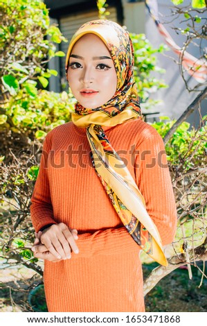 Portrait of a beautiful Asian woman wearing stylish bright outfits with hijab in a real environment. Muslim female hijab fashion portraiture concept.