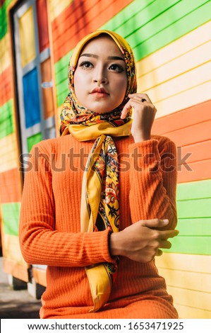 Portrait of a beautiful Asian woman wearing stylish bright outfits with hijab in a real environment. Muslim female hijab fashion portraiture concept.