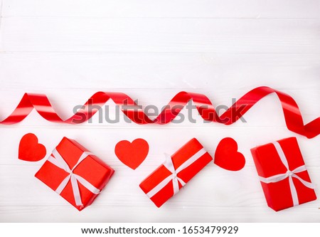 Red ribbon, paper heart and box isolated on white background. The concept of the holidays