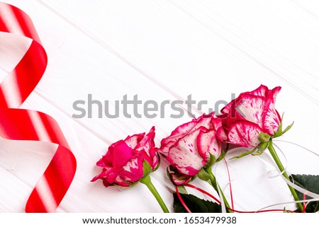 Red ribbon and roses isolated on white background. The concept of the holidays