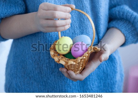 Hands holding a small basket containing painted eggs for Easter celebrations close up