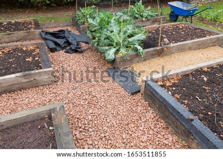 Laying weed control fabric or weed membrane and a gravel path in a vegetable garden, UK Royalty-Free Stock Photo #1653511855