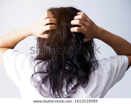 Asian woman with long black hair scratching head from itching and having messy hair.