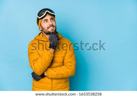 Young skier caucasian man isolated looking sideways with doubtful and skeptical expression.