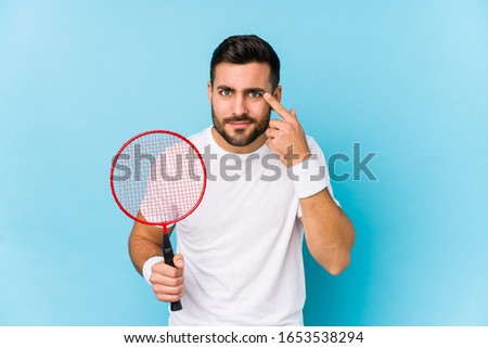 Young handsome man playing badminton isolated showing a disappointment gesture with forefinger.