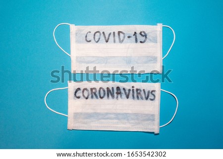 Coronavirus word written on a surgical medical face mask. Wuhan , 2019-nCoV blue backgeound. 
