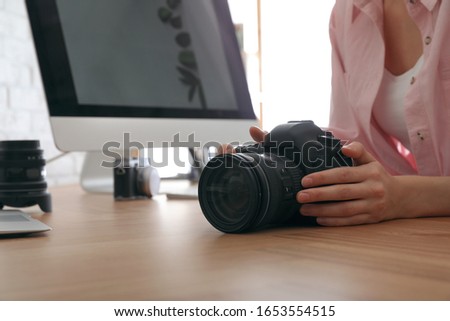 Professional photographer with camera working at table in office, closeup