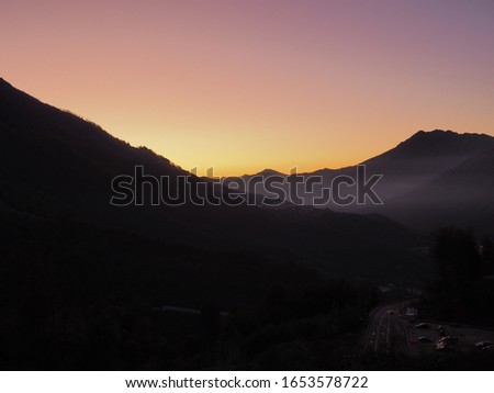 The road in the mountains on a background of red-yellow sunset sky