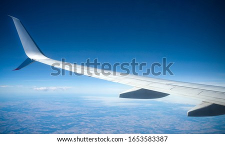 Wing of the plane lit by the sun on a background of sky and city, Spain