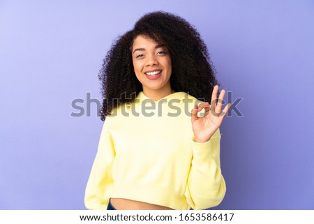 Young african american woman isolated on purple background showing ok sign with fingers