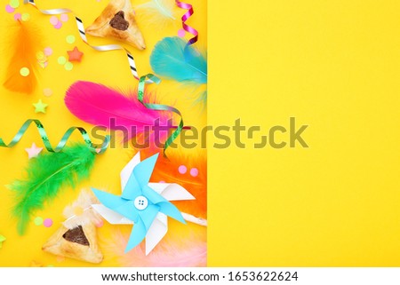 Purim holiday composition. Cookies with party supplies on yellow background