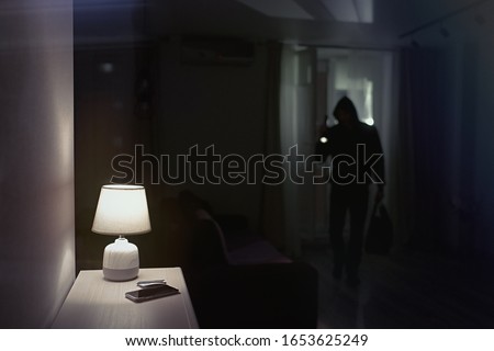 Burglar inside of a house with flashlight                             Royalty-Free Stock Photo #1653625249