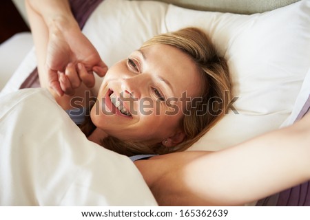 Attractive Middle Aged Woman Waking Up In Bed Royalty-Free Stock Photo #165362639