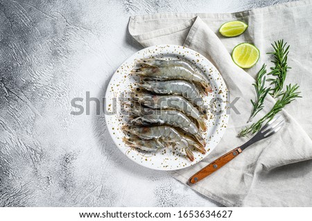 Fresh raw tiger prawns, shrimps and spices on a white plate. Gray background. Top view. Copy space Royalty-Free Stock Photo #1653634627