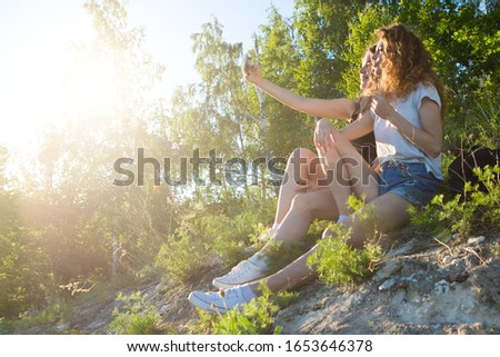 A world without borders. Stunning journey of two girls in the mountains. two attractive young girls travel together, do selfie on the phone against the sky and landscape in the mountains in the sun