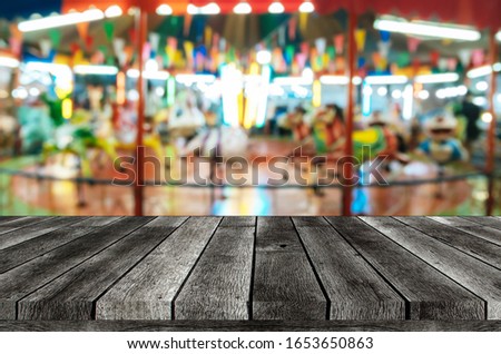 empty grey top table or wooden terrace with abstract blurred image of carousel horses in public event festival at park, copy space for display product or object presentation, advertisement concept